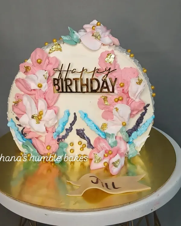 A beautiful birthday cake with a painted floral design made with buttercream.