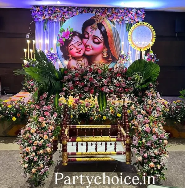 We create stunning, flower-dense setups for naming ceremonies. This traditional cradle (thottil) is surrounded by a lavish arrangement of fresh flowers, with a personalized backdrop featuring mother and child imagery to make the day truly special.