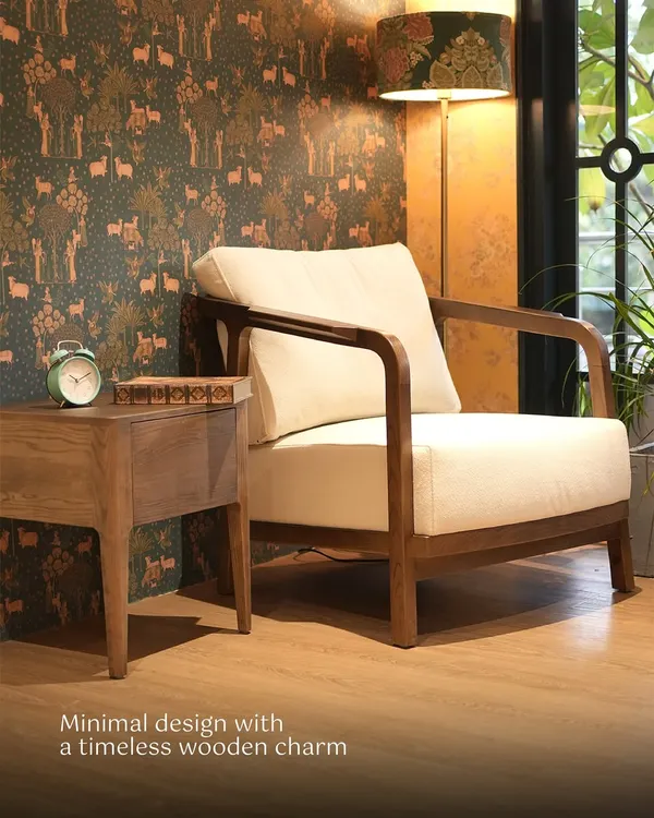 This armchair features a minimalist wooden frame and plush, off-white cushions, creating a timeless look. It's the perfect companion for a quiet reading corner, paired here with a matching side table.