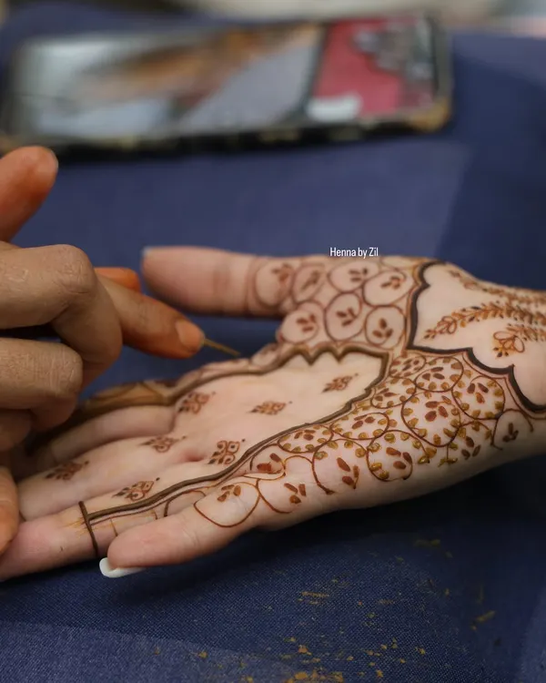 A close-up shot of me applying henna to a client's palm. You can see the fine lines and delicate floral details taking shape, a process that requires immense focus and a steady hand.