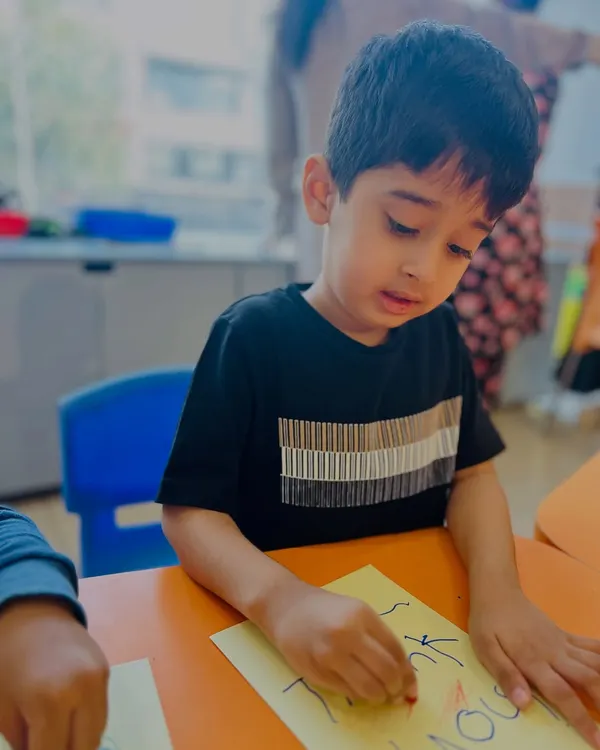 A young boy in our speech and drama class concentrates on writing or drawing, an activity that helps build the focus needed for performance and self-expression.