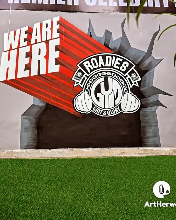 A powerful 3D mural for Roadies Gym, featuring their logo bursting through a wall. The "WE ARE HERE" text uses forced perspective to create a dynamic, eye-catching effect.