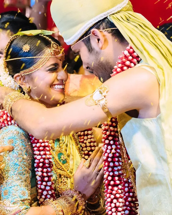A candid, joyous moment from the Chola-inspired wedding. This captures the happiness of the couple during the ceremony, with a focus on the bride's radiant smile and traditional jewelry.