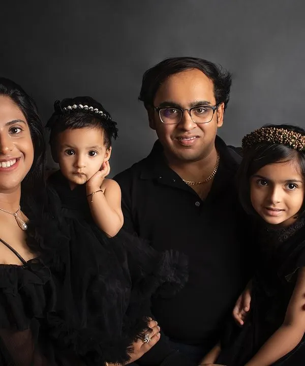 A classic and elegant family portrait against a dark backdrop. Coordinated black outfits create a timeless look that emphasizes their connection.