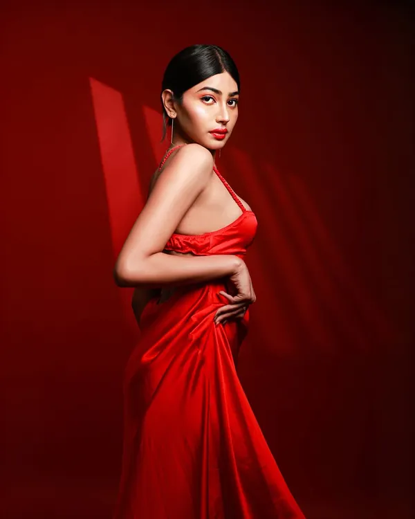 A model in a flowing red satin dress against a solid red background, with dramatic lighting creating shadows that accentuate her form. This is a perfect example of a monochromatic, high-impact studio shot.