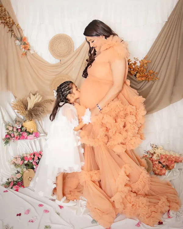 The sweetest kiss for a new sibling. A big sister-to-be gives a gentle kiss to her mommy's baby bump, a truly precious and heartwarming moment.