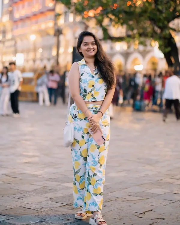 A bright and cheerful portrait taken in a busy plaza. Her lemon-print outfit and happy smile perfectly match the sunny day and lively background.