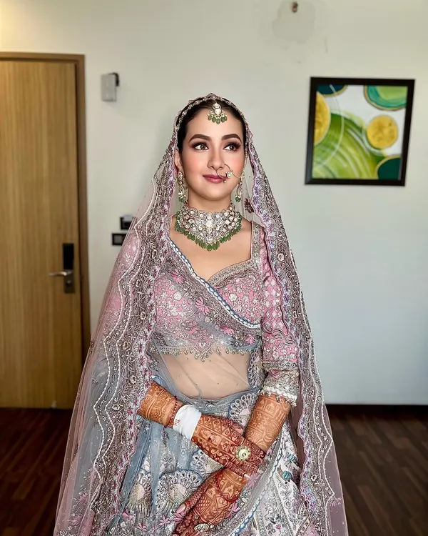 A beautiful bride ready for her wedding. The hair is styled in a clean, traditional updo, secured neatly under the dupatta and adorned with a maang tikka, creating a flawless and regal profile.