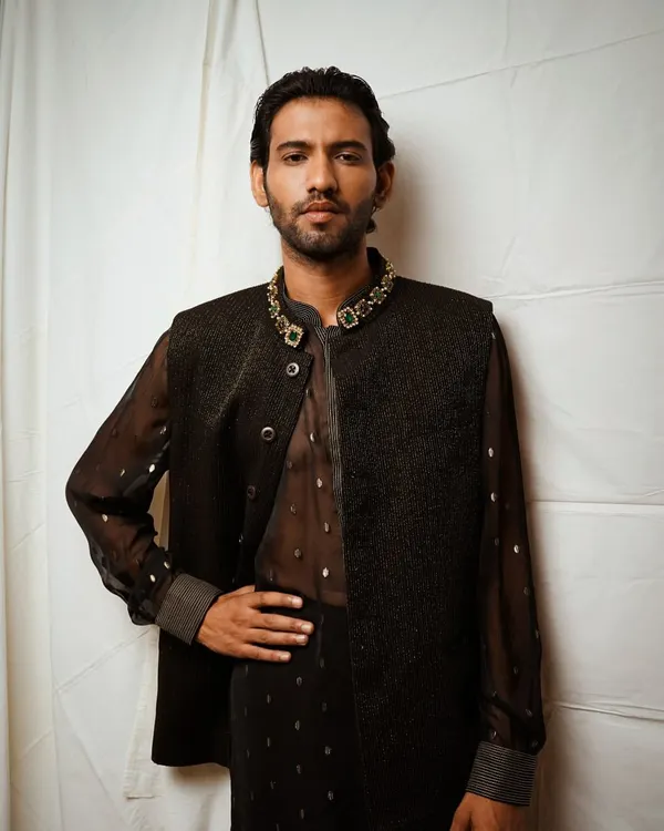 A strong, classic pose for a men's fashion portfolio. This shot highlights the elegant details of the embellished collar and the texture of the vest, creating a look of modern sophistication.