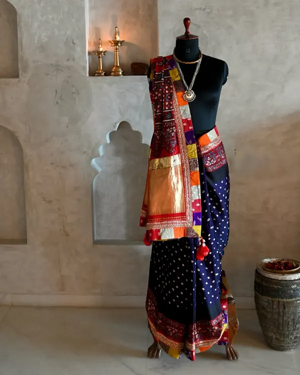 A full view of a bespoke saree, crafted from hand-dyed silk with Bandhni dots and an Ajrakh patchwork pallu. The piece is brought together with Zardozi embroidery and fragments of Banarsi fabric, creating a rich tapestry of Indian textile arts.