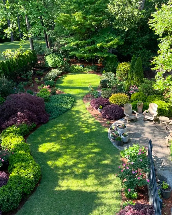 This is the kind of garden that makes you feel like you have everything you need right at home. I designed this space with a mix of lush green lawn, a stone patio for seating, and layered plantings with varied colors and textures to create a private, natural escape.