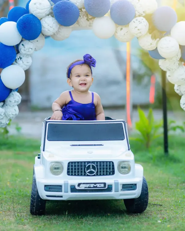 Making a grand entrance. This fun shot features a baby girl in a miniature Mercedes G-Wagon, part of a creative pre-birthday photoshoot with fun props.
