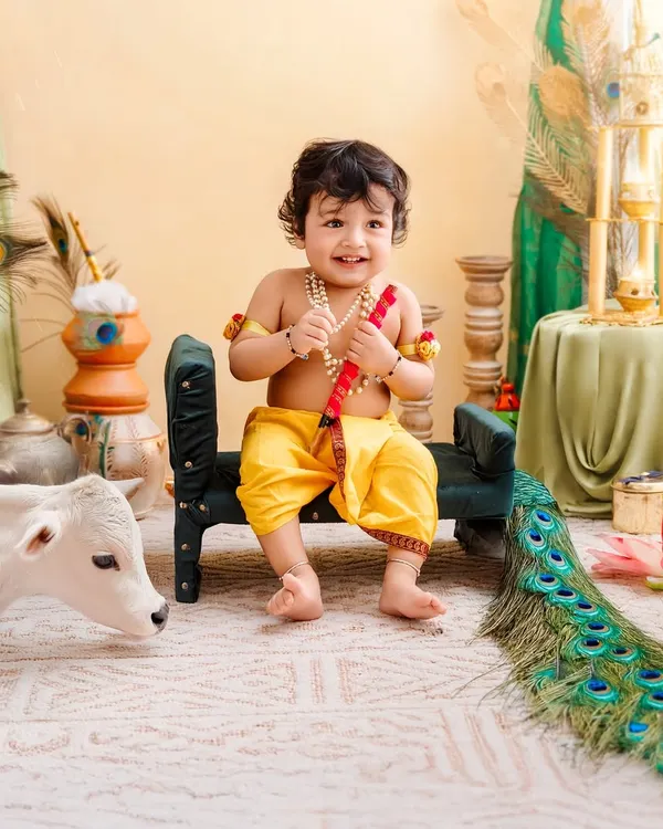 Our little Krishna smiles happily, sitting with his flute and a friendly calf in this detailed Janmashtami setup.