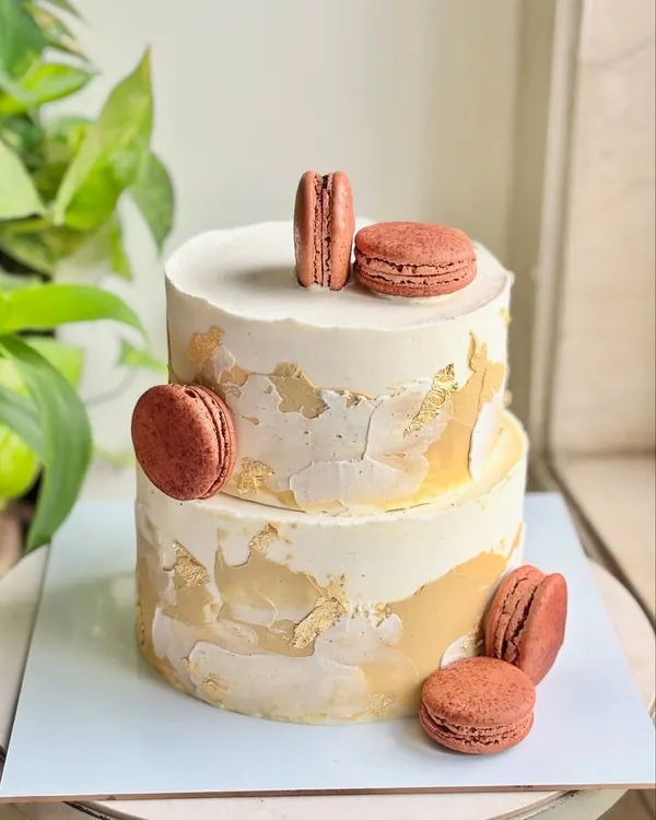 For a dad who deserves nothing but timeless elegance. This minimal, modern two-tier cake features a textured buttercream finish with gold leaf accents and is adorned with delicious macarons.