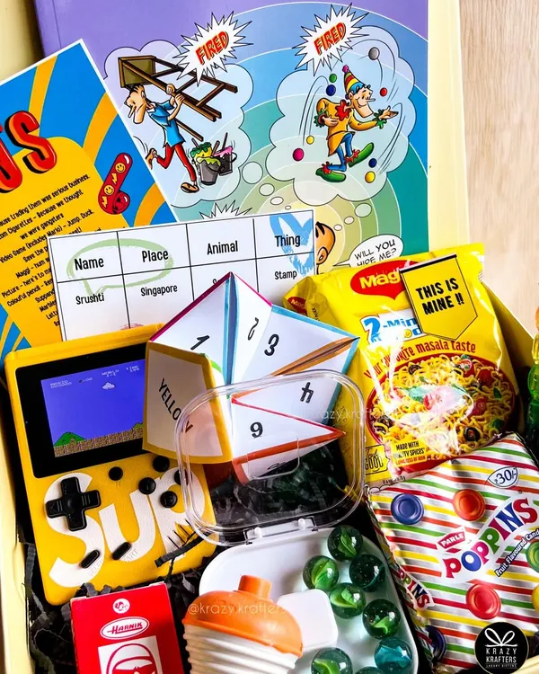 Our 90s Kid Nostalgia box is a blast from the past! It's filled with a brick video game, Poppins candy, Phantom cigarettes, a Tinkle comic, and a 'lattu' (spinning top).