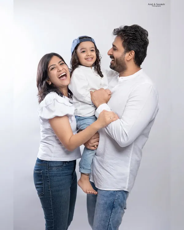 Laughter is the best accessory. This candid studio family portrait captures the pure happiness and love between parents and their child in a simple, classic setting.