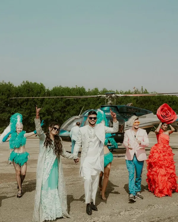 The grand arrival continues. This shot captures the couple and their entourage walking away from the helicopter, full of energy and style, ready to kick off an unforgettable wedding celebration.