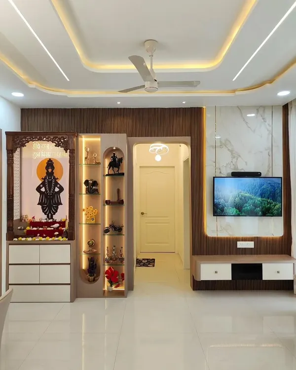 This is what we mean by a complete home transformation. We designed this open-plan space to seamlessly integrate the living room, dining area, and a custom pooja mandir. Notice the cohesive design language, from the wooden paneling and marble-finish TV wall to the ambient lighting in the false ceiling, creating a home that is both luxurious and welcoming.
