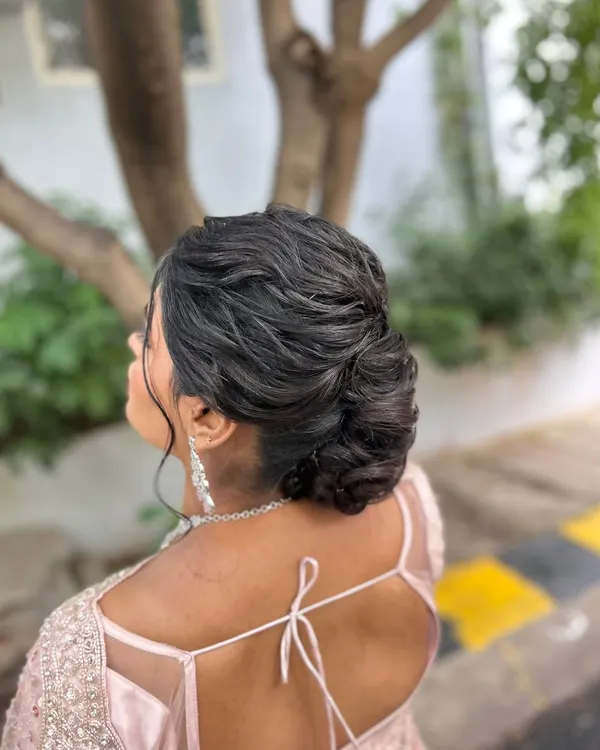 A soft, textured low bun with gentle wisps framing the face, creating a romantic and effortless look.