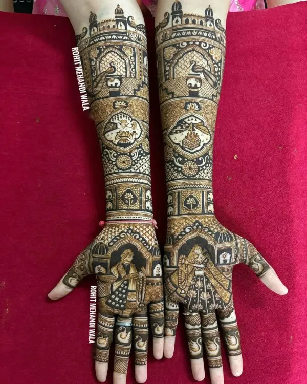 This full-arm design features a beautiful bride and groom portrait on the palms, set within an arch. The artwork extends up the arms with traditional symbols like the kalash, showcasing a blend of personal and classic elements.