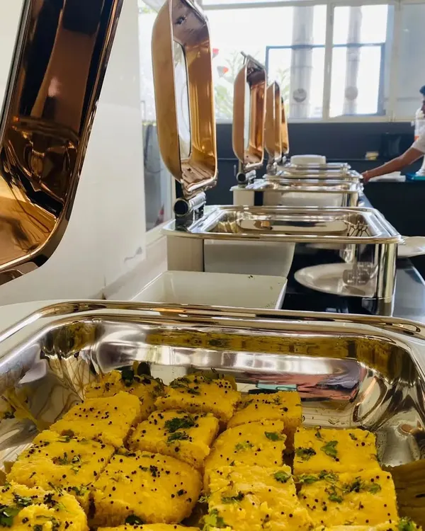 A glimpse of our buffet setup for a corporate client. Here, fresh and fluffy dhokla is ready to be served from professional chafing dishes, ensuring the food stays warm and inviting for your team.