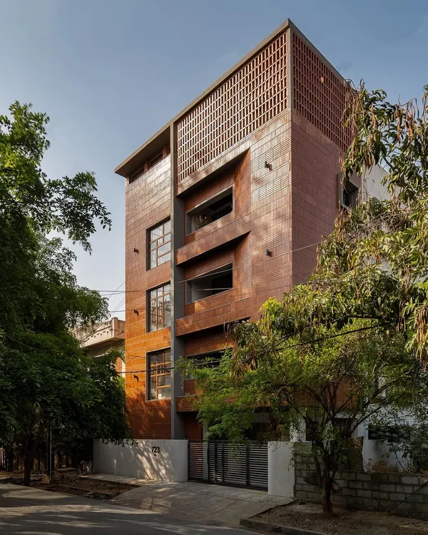 A full view of Project 723's facade, showcasing the use of linear bricks in both soldier and stretcher bonds. The arrangement creates a textured, monolithic appearance, punctuated by recessed windows and balconies.