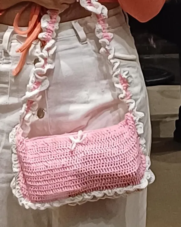 A close-up of my pink and white ruffle shoulder bag. The ruffles on the strap and body give it that super cute coquette look. You can see the little bow detail here too!