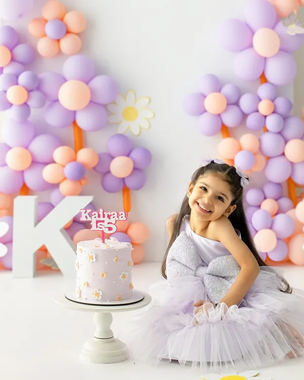 A fifth birthday blooming with joy. This beautiful shot captures the birthday girl's radiant smile against a custom backdrop of pastel, daisy-like balloons, perfectly matching her party dress.