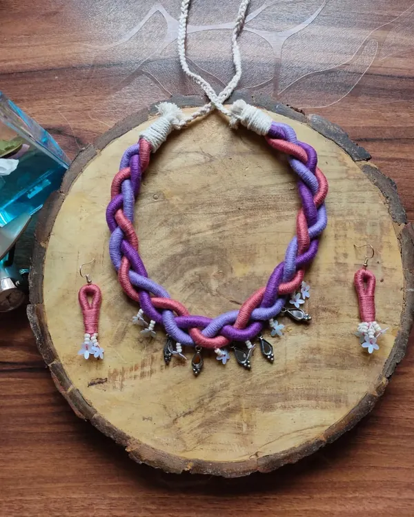 This braided thread necklace in shades of purple and pink is a true statement piece. It's surprisingly lightweight and comes with matching earrings, making it perfect for pairing with a simple saree or top.
