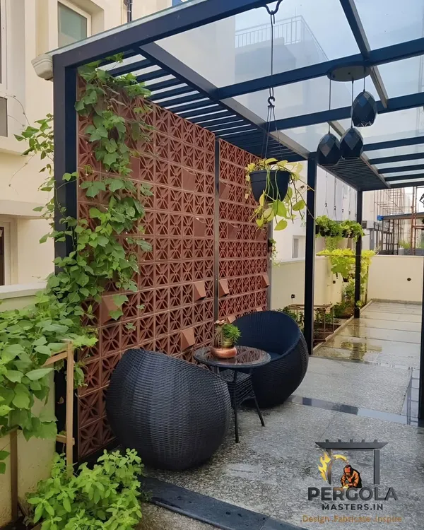 This cozy patio corner demonstrates how we integrate different elements. We installed a glass pergola for rain protection and a terracotta jali wall for privacy and airflow, creating a comfortable and secluded outdoor seating nook.