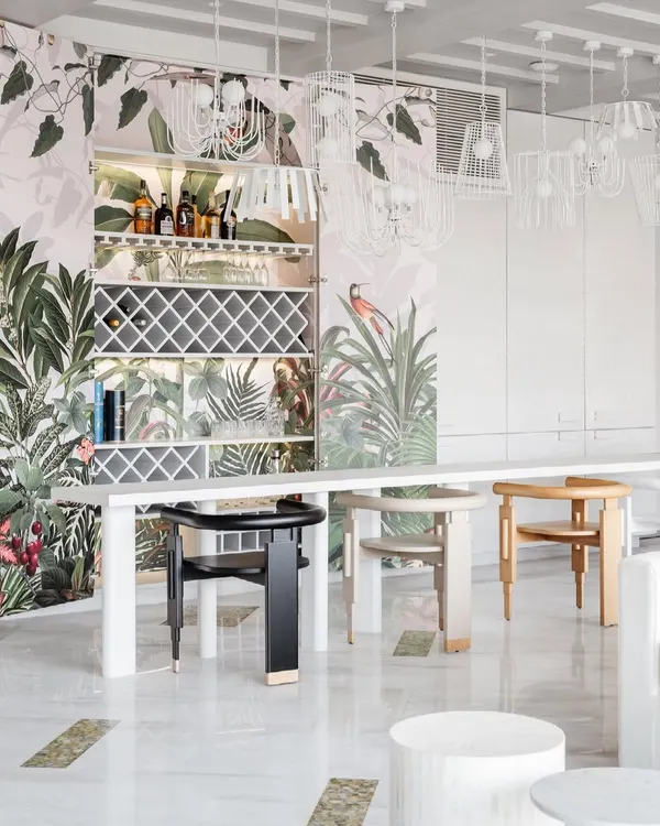 The 'Reveal Bar' from House No. 7 is a favorite piece. Clad in tone-on-tone paneling, it blends into the wall, but opens to reveal a paradise of Birds of Paradise wallpaper, transforming the space instantly.