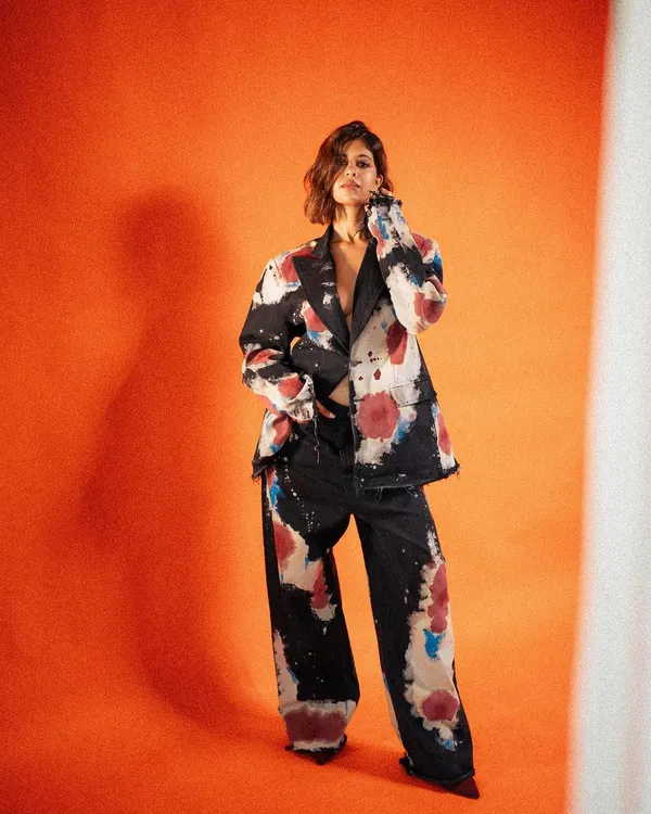 A full-length shot for an Apple campaign with Sejal Kumar, featuring a hand-painted suit by Huemn. The bold orange background makes the artistic outfit pop, creating a powerful and fashion-forward image.
