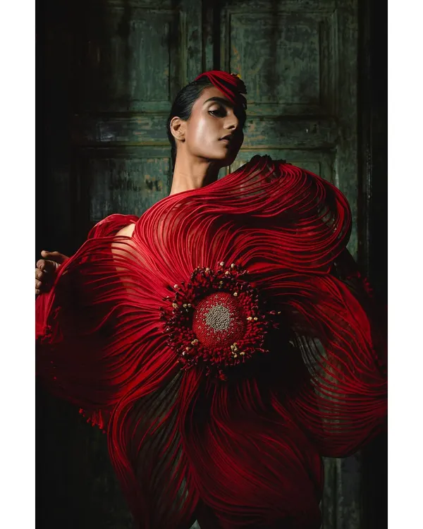 A powerful shot from the Vaishali S. campaign, where the model wears a stunning red creation that resembles a blooming flower. The styling is minimal otherwise, allowing the sculptural couture piece to be the undisputed focus.