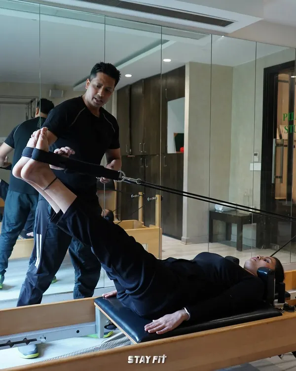 I believe in hands-on guidance. Here, I'm helping a client perfect her leg press form on the reformer, ensuring she engages the right muscles for maximum benefit and injury prevention.