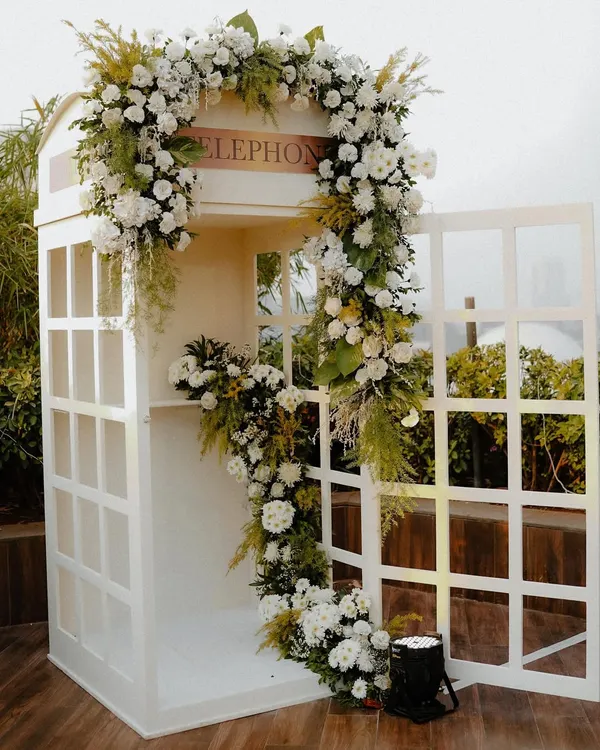 Our bespoke audio guestbook, housed in a classic white telephone booth adorned with flowers. This unique feature allows guests to leave voice messages, creating a cherished audio keepsake for the couple.