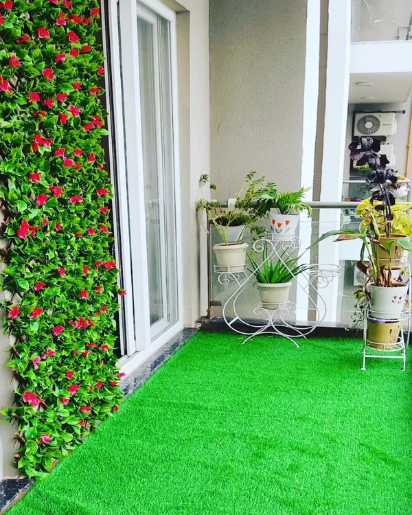 A complete balcony makeover. I installed a soft artificial grass floor and a vibrant vertical garden wall with red flowers, instantly adding color and life to the space.