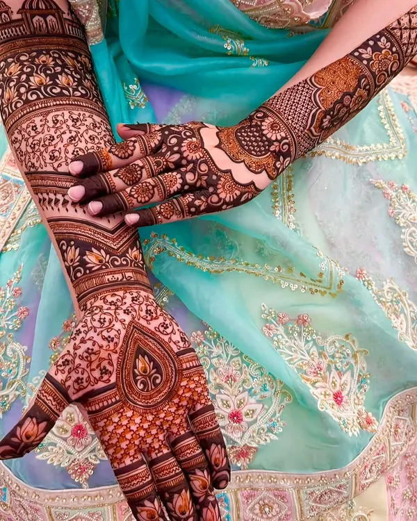 A stunning close-up of full coverage bridal mehndi. This design features a mix of floral, paisley, and geometric patterns with a beautiful teardrop motif on the palm.