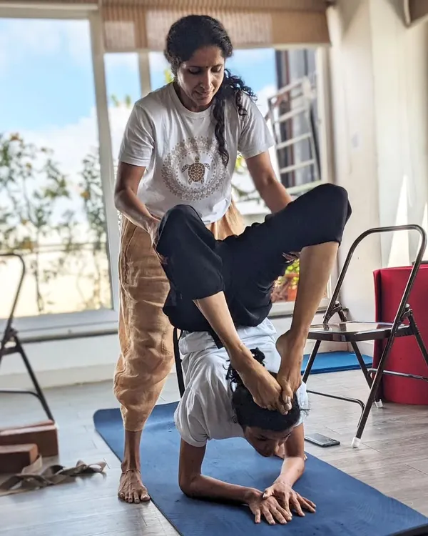 Our Guru-Shishya tradition in action. We believe in direct, hands-on mentorship to guide you safely into the deepest expressions of yoga. Here, a student receives expert assistance in Vrischikasana, building trust and unlocking potential.