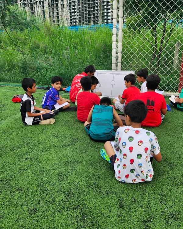 Learning the game from a different perspective. A coach uses the whiteboard to explain formations and player roles to our young athletes, building their football IQ.