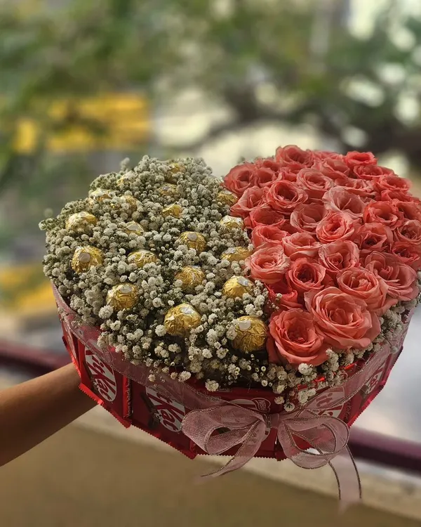 A stunning heart-shaped bouquet perfect for Valentine's Day or an anniversary. This arrangement is half fresh pink roses and half Ferrero Rocher chocolates nestled in baby's breath.