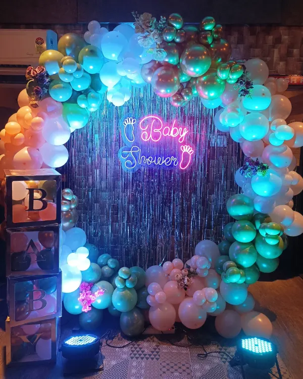 A closer look at this modern baby shower backdrop. The combination of the 'Baby Shower' neon sign against the shimmer curtain and multi-colored balloons creates a fantastic effect in photos.