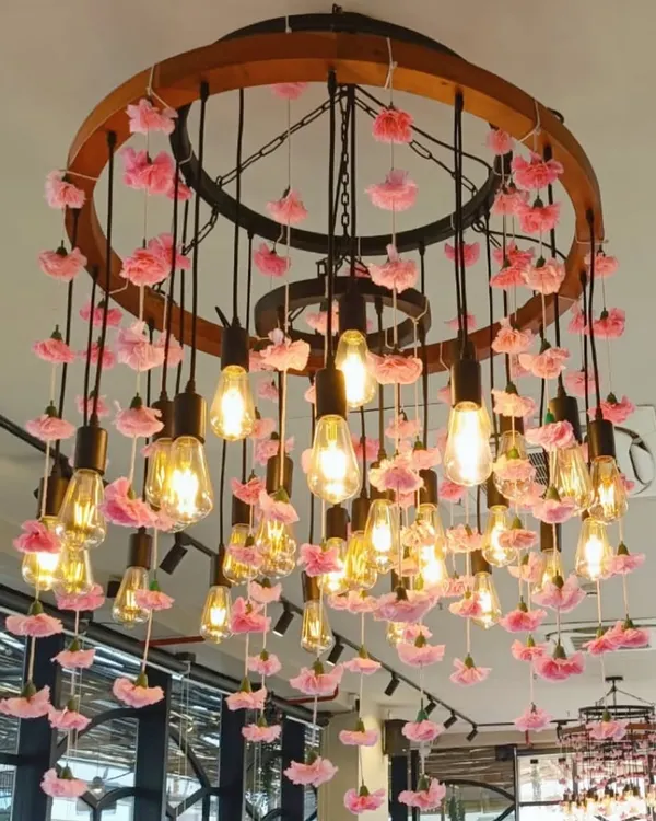 Lighting is a key element of our designs. This custom chandelier, featuring exposed Edison bulbs adorned with delicate pink flowers, created a warm and romantic glow, serving as a stunning centerpiece for the entire room.