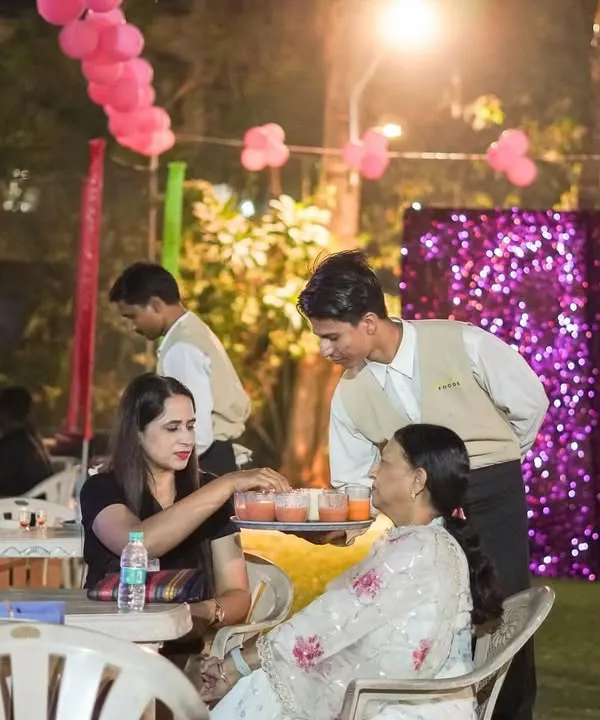 My team is dedicated to providing attentive service to every guest. Here, a staff member is serving drinks to guests seated at an outdoor birthday party.