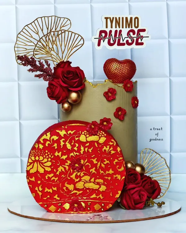 An elegant corporate cake designed for Tynimo Pulse. The sophisticated red, gold, and beige color scheme and intricate details make it a perfect centerpiece for a company celebration or brand event.