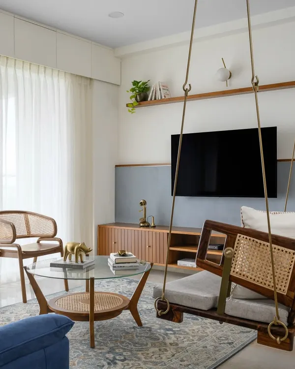 The living space in our 'Malhar' project is centered around a traditional Indian swing. The sleek veneered TV unit and textured half-wall create a contemporary classical feel, completed by rattan chairs.