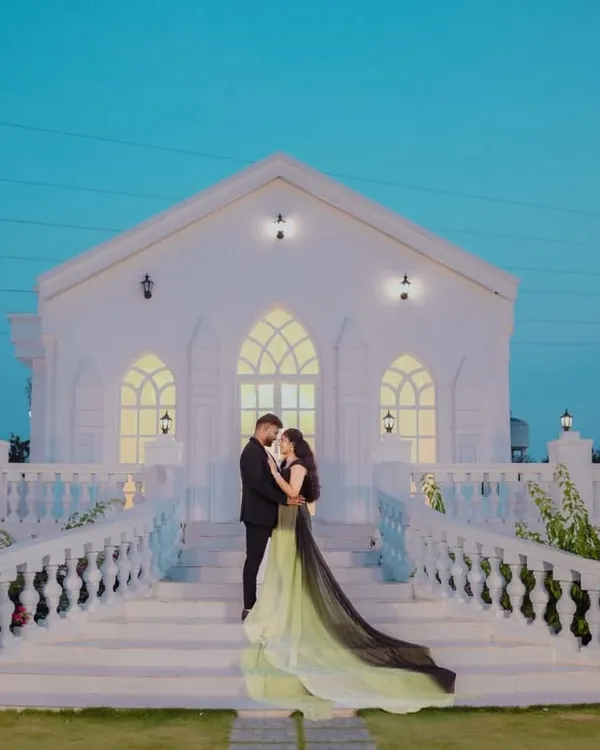 A romantic pose in front of a beautiful white chapel. The lime and black trail gown creates a striking silhouette, showing how a unique dress can make a pre-wedding photo unforgettable.