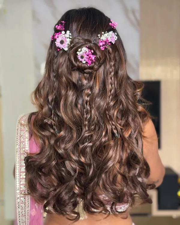This intricate half-up style is perfect for a Mehendi or Sangeet. I combined soft waves with delicate braids and a floral bun created with fresh pink and white flowers to create a romantic, bohemian look.