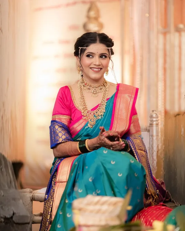 A candid moment of joy. This South Indian bride looks radiant in her peacock-blue and pink Kanjeevaram saree, her happiness shining through our timeless makeup application.