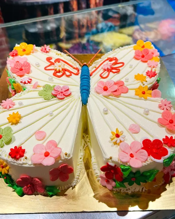A stunning butterfly-shaped cake decorated with a garden of colorful buttercream flowers. This unique sculpted cake is perfect for a spring or garden-themed party.