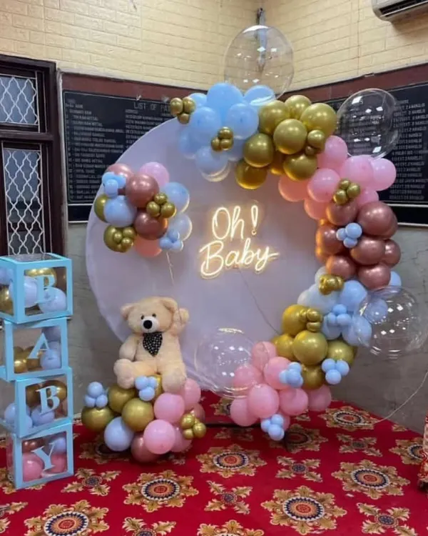 A classic 'Oh Baby' shower setup with a gender neutral color scheme. I used a round backdrop with a neon sign, a balloon garland in pink, blue, and gold, and a cute teddy bear prop.